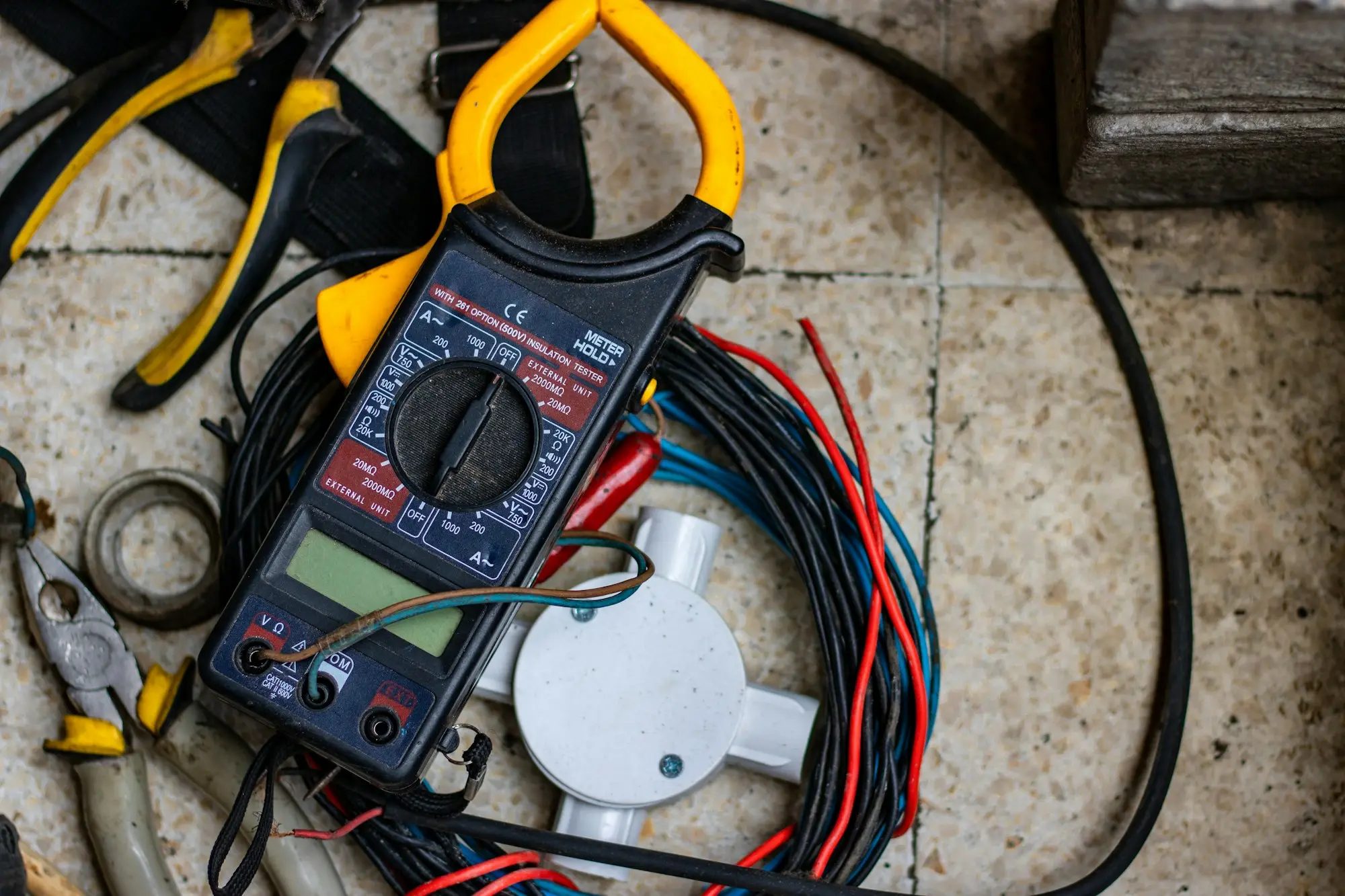 Electrician's multimeter and tools laid out on the floor