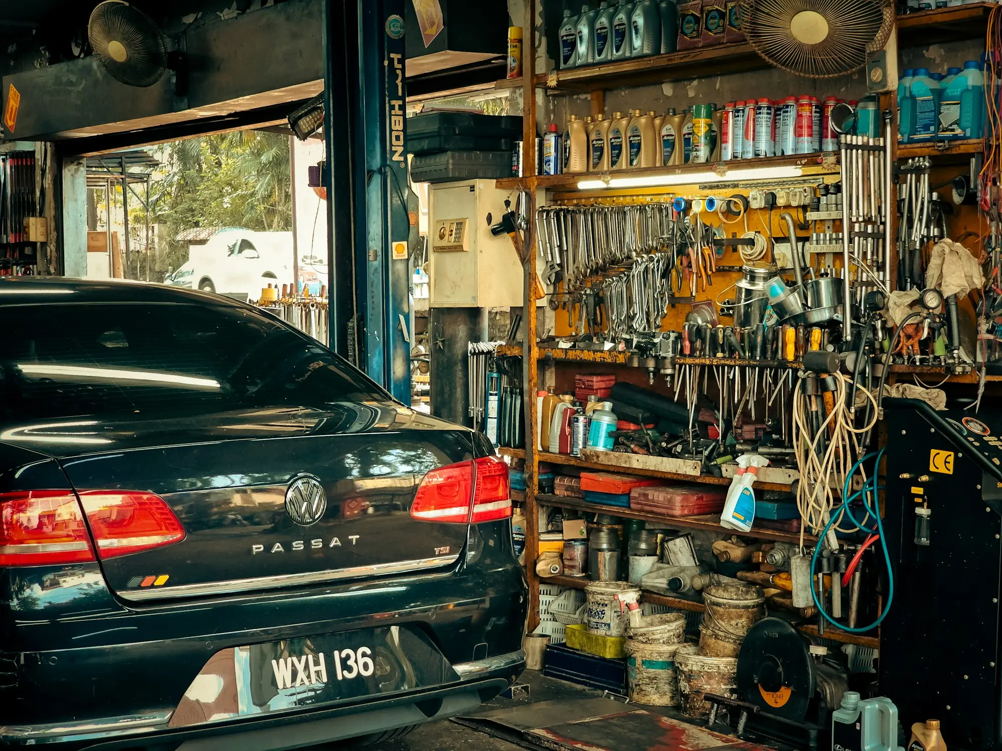 Car on a hoist in a mechanic's workshop lined with tools
